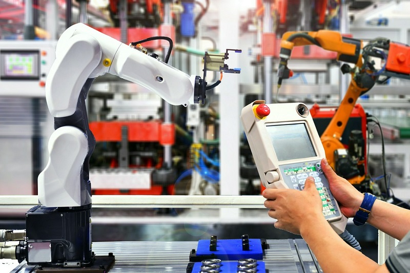 mężczyzna nadzorujący roboty przemysłowe na linii produkcyjnej
